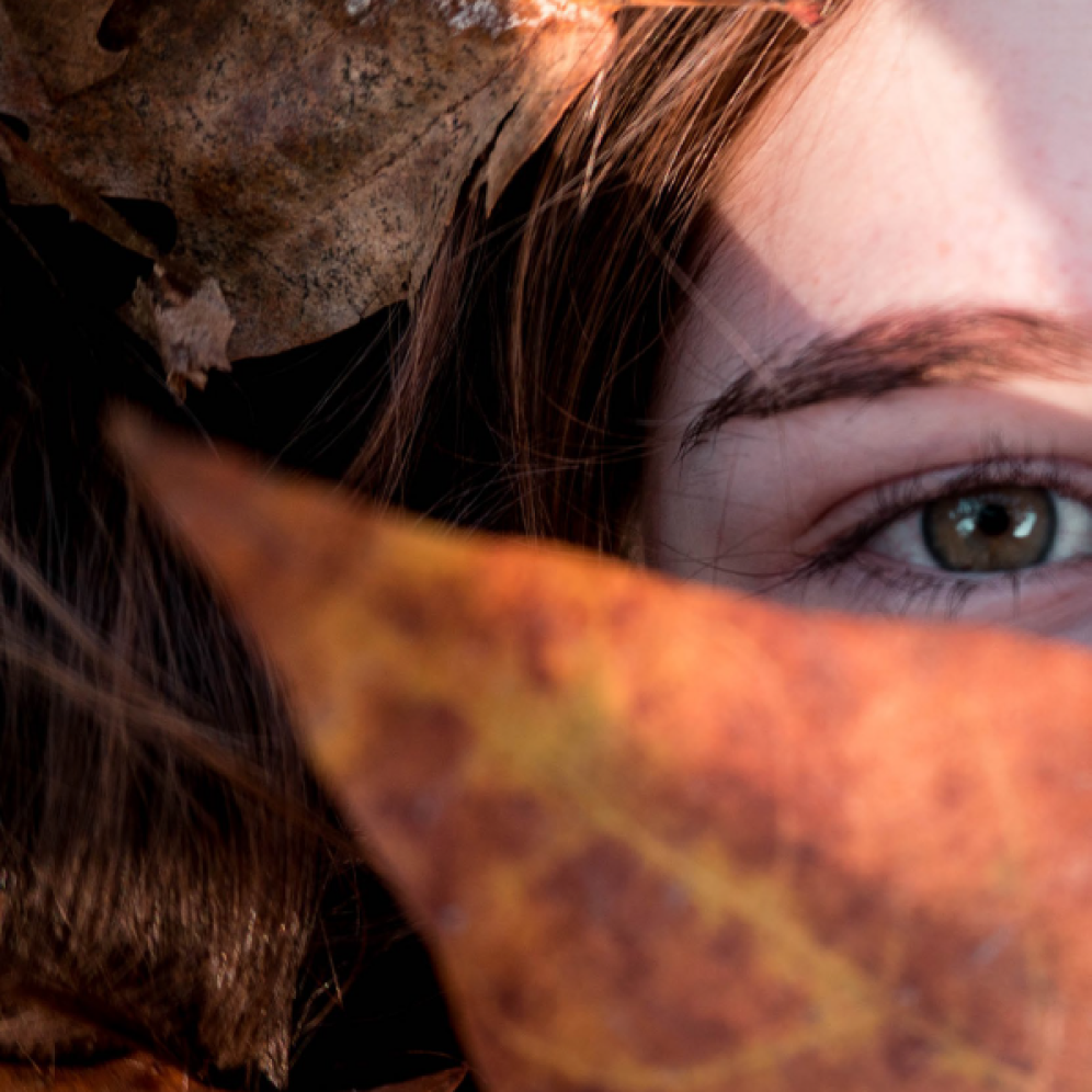 A kid watching the sky while laying on autumn leaves